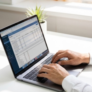 Hands comfortably typing on a sleek, modern laptop keyboard on a minimalist white desk in natural light.